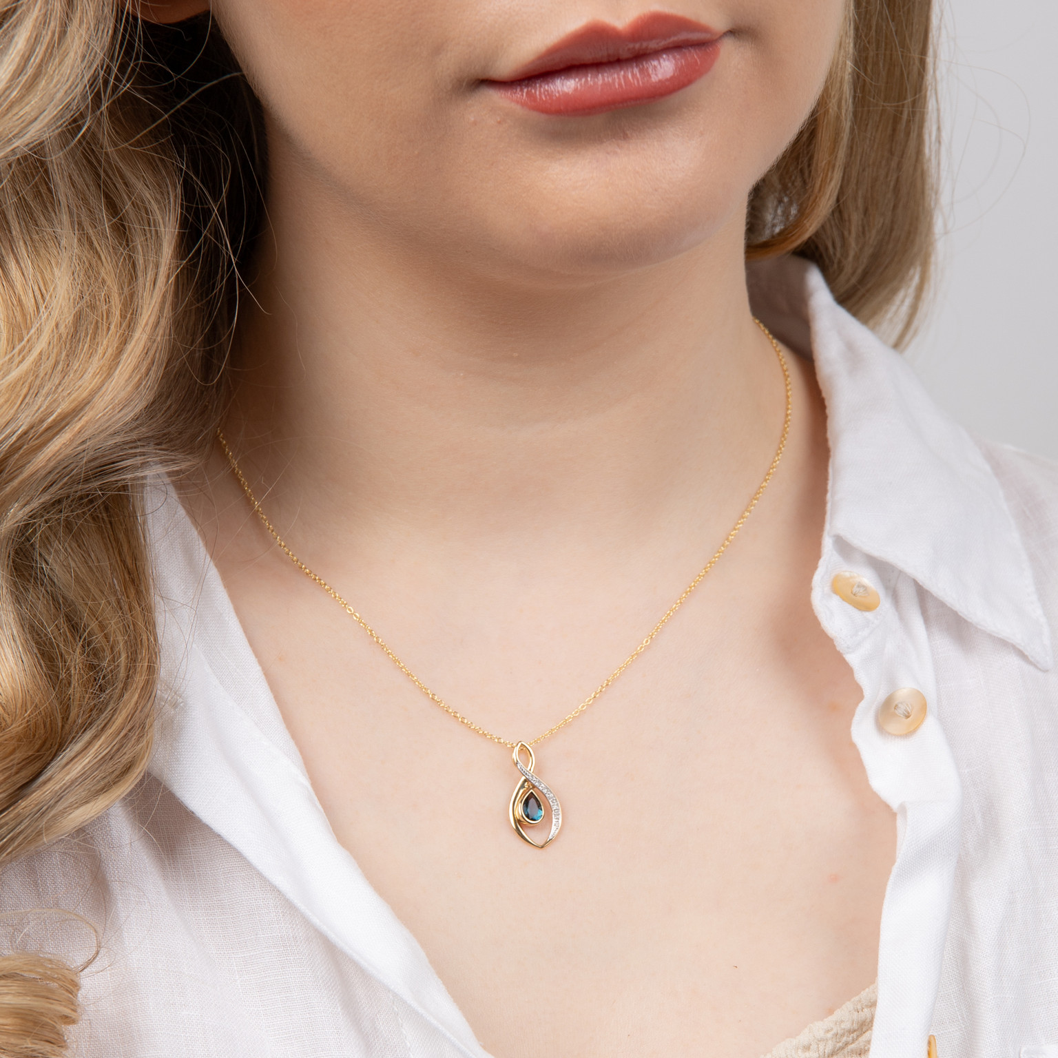 9ct yellow gold pendant with blue topaz and diamonds, worn